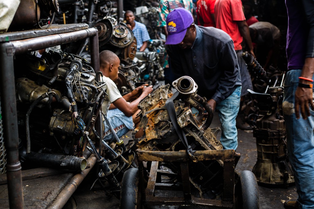 Mechanics assembling a Toyota engine in a busy Lagos auto parts district